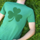 Man lays in field wearing green shamrock shirt