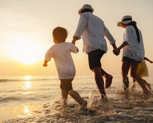 Side view of a happy family on vacation running towards beach at sunset