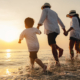 Side view of a happy family on vacation running towards beach at sunset